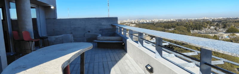 Terraza corporativa con mobiliario de hormigón moldeado in situ y vistas panorámicas.
